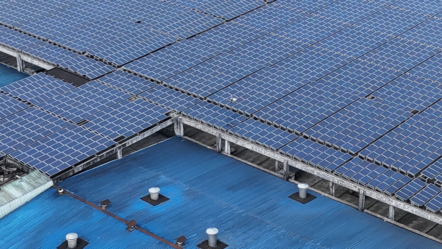 Vista aérea de paneles solares instalados en el tejado de un edificio industrial, representando la descarbonización del sector manufacturero.
