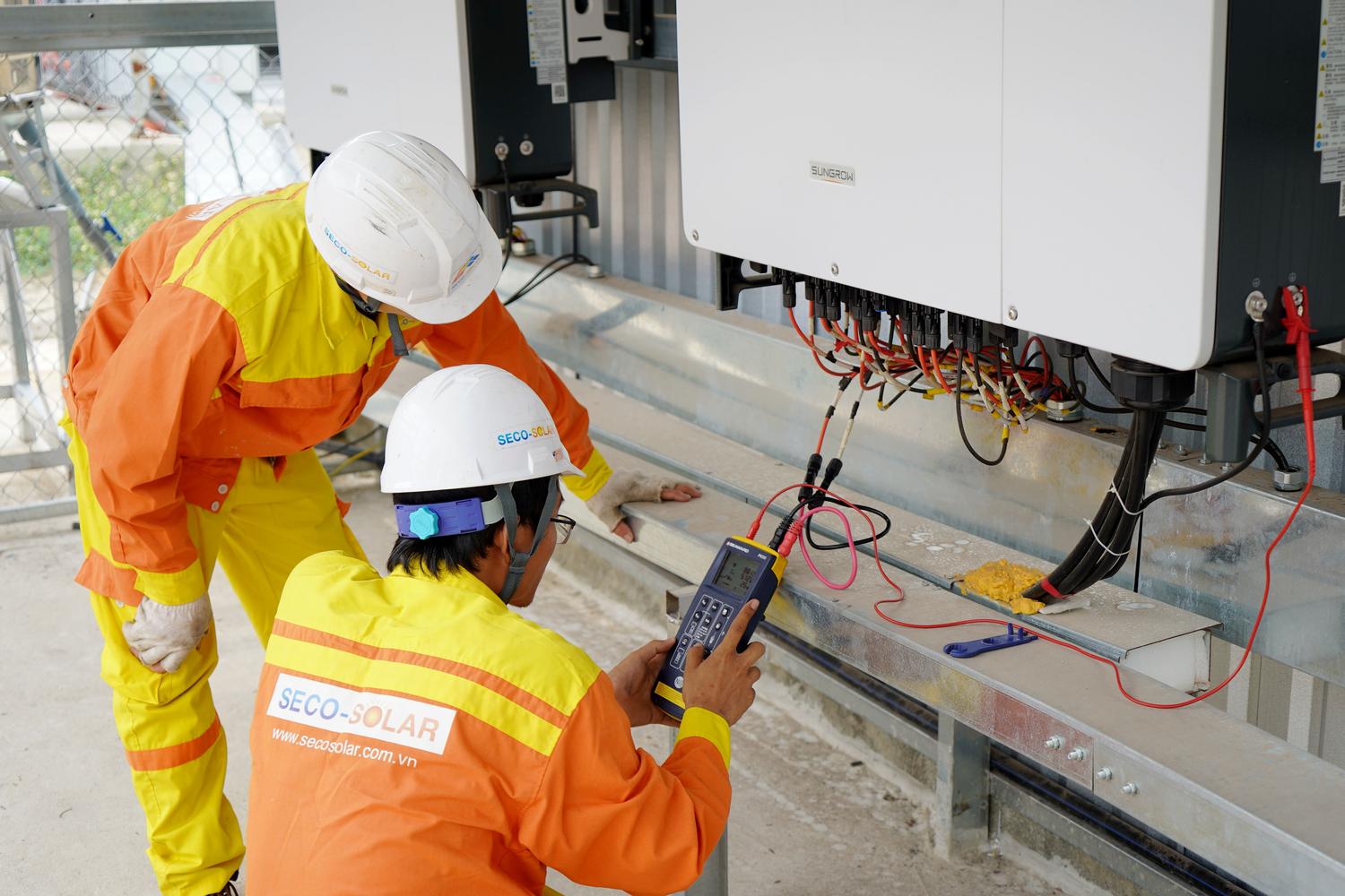 Ingenieros eléctricos instalando y probando sistemas de energía solar, ilustrando los costes de instalación y mantenimiento.