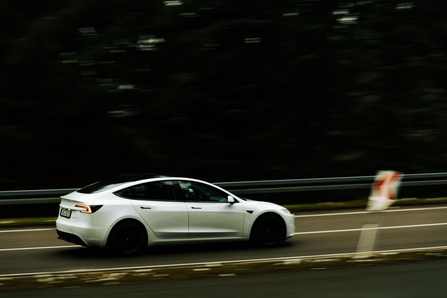Coche eléctrico moderno circulando a alta velocidad por una autopista, representando la autonomía en viajes largos.
