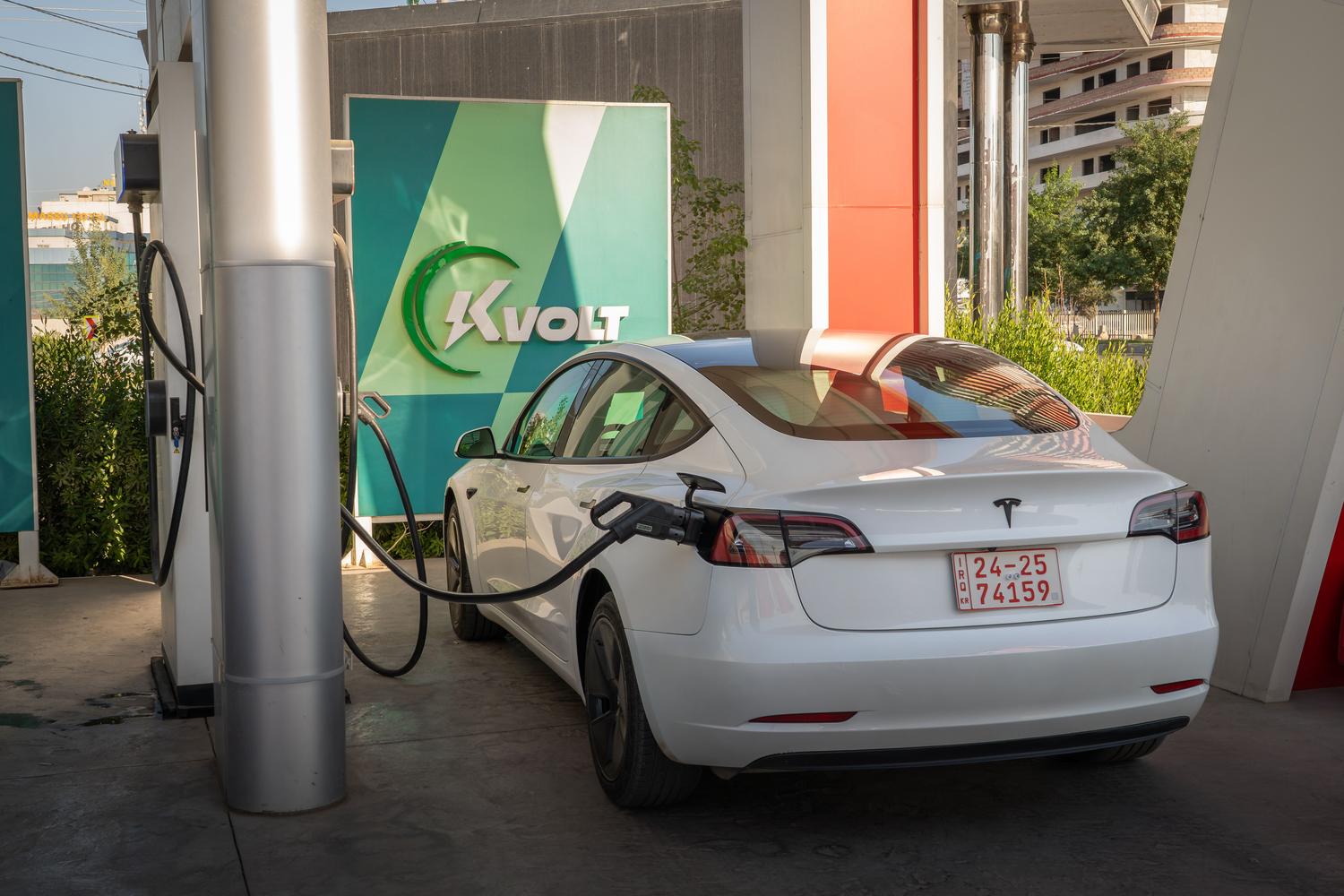 Vehículo eléctrico blanco cargando en una estación de carga pública moderna.