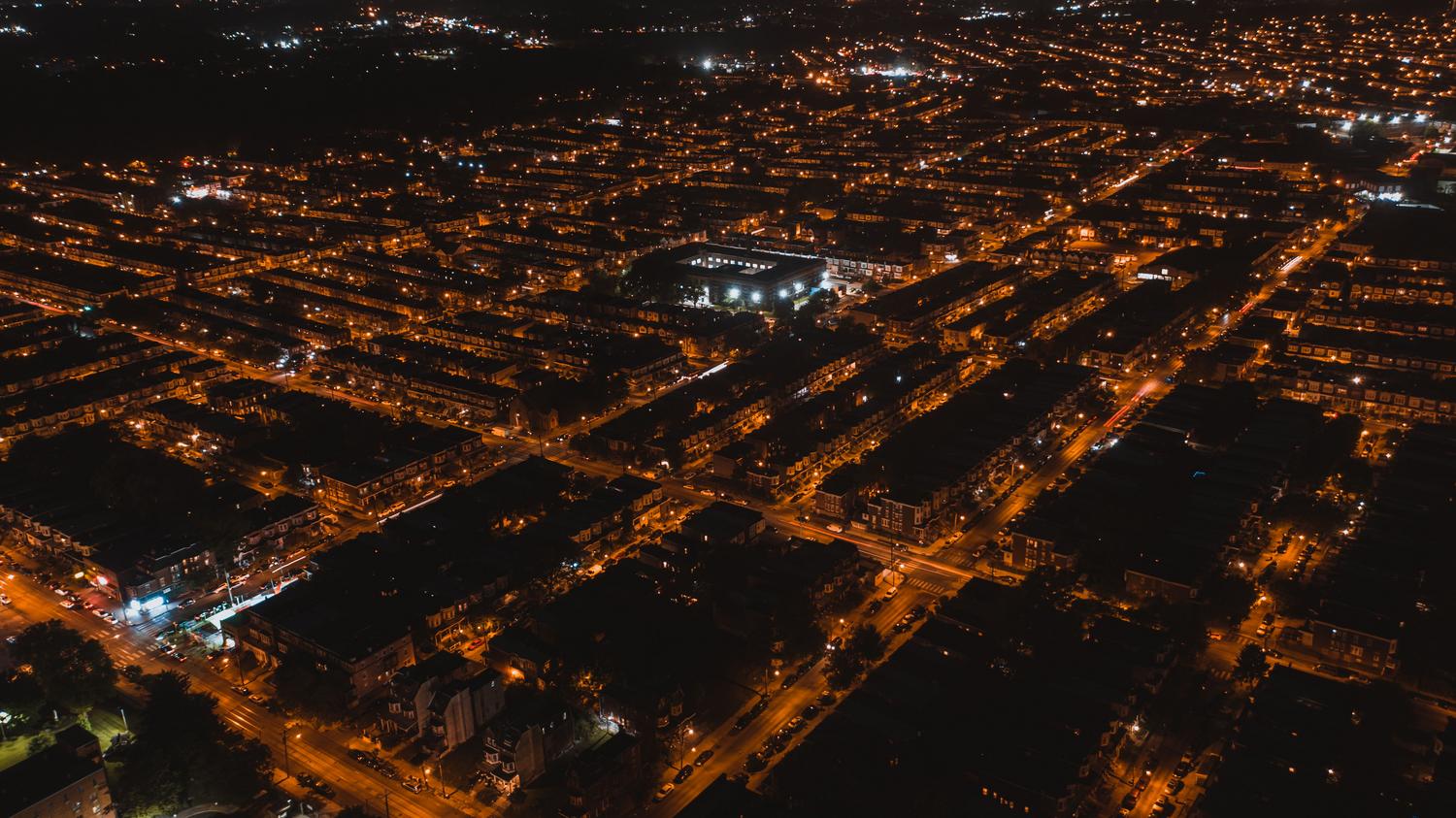 Vista aérea de una red de calles urbanas iluminadas ineficientemente, mostrando el desperdicio de luz hacia el cielo y el efecto de luz dispersa. Vista aérea de una red de calles urbanas iluminadas ineficientemente, mostrando el desperdicio de luz hacia el cielo y el efecto de luz dispersa.