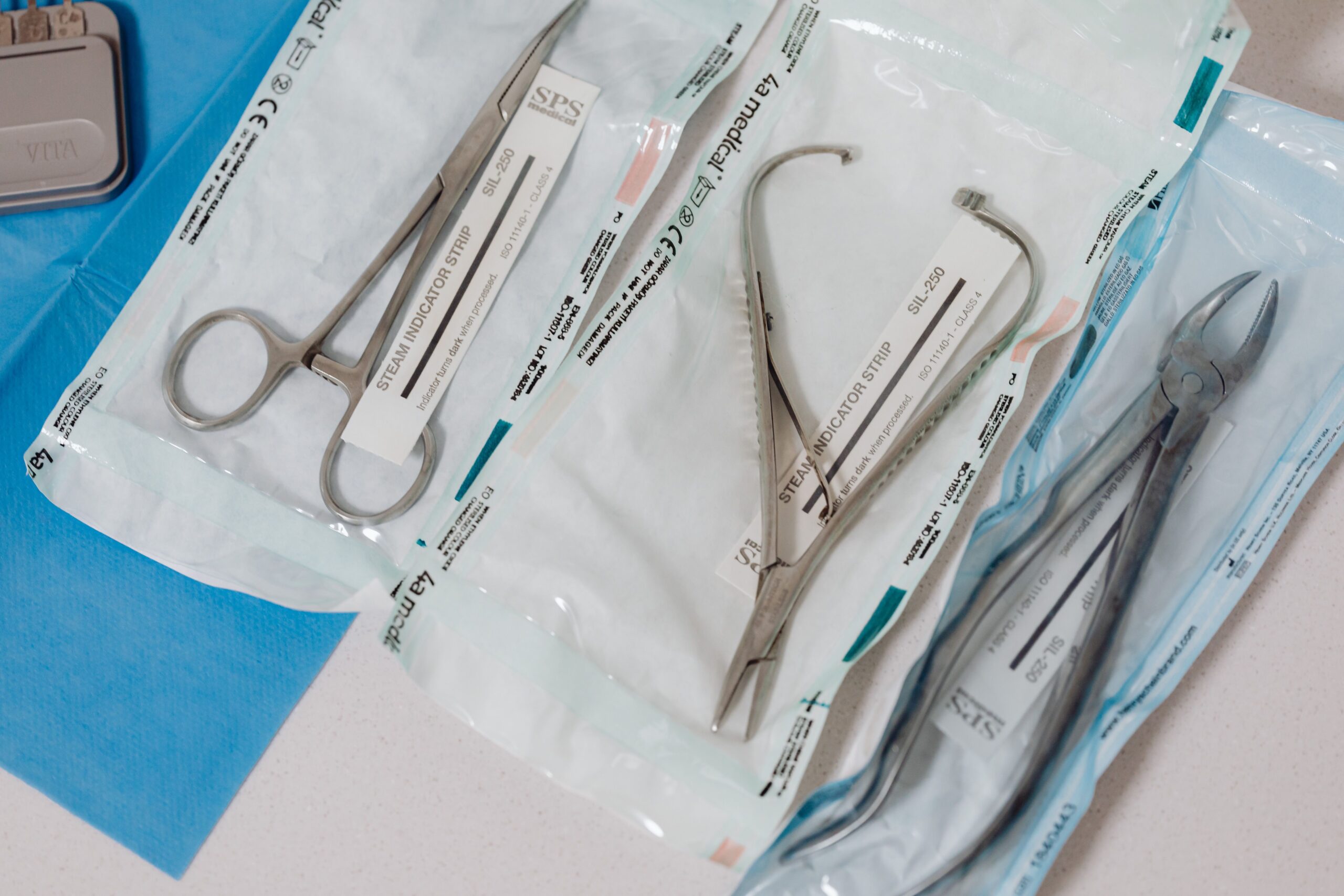 Primer plano de instrumental quirúrgico esterilizado y empaquetado en bolsas selladas sobre una mesa clínica.