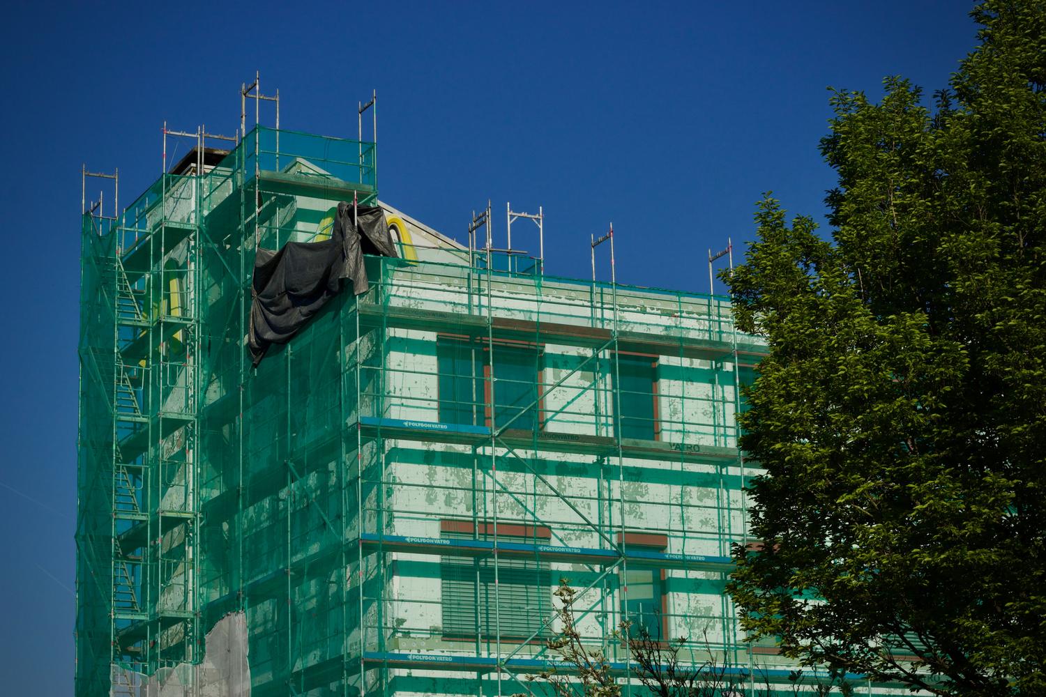 Edificio público en proceso de rehabilitación energética cubierto por andamios y mallas de seguridad.