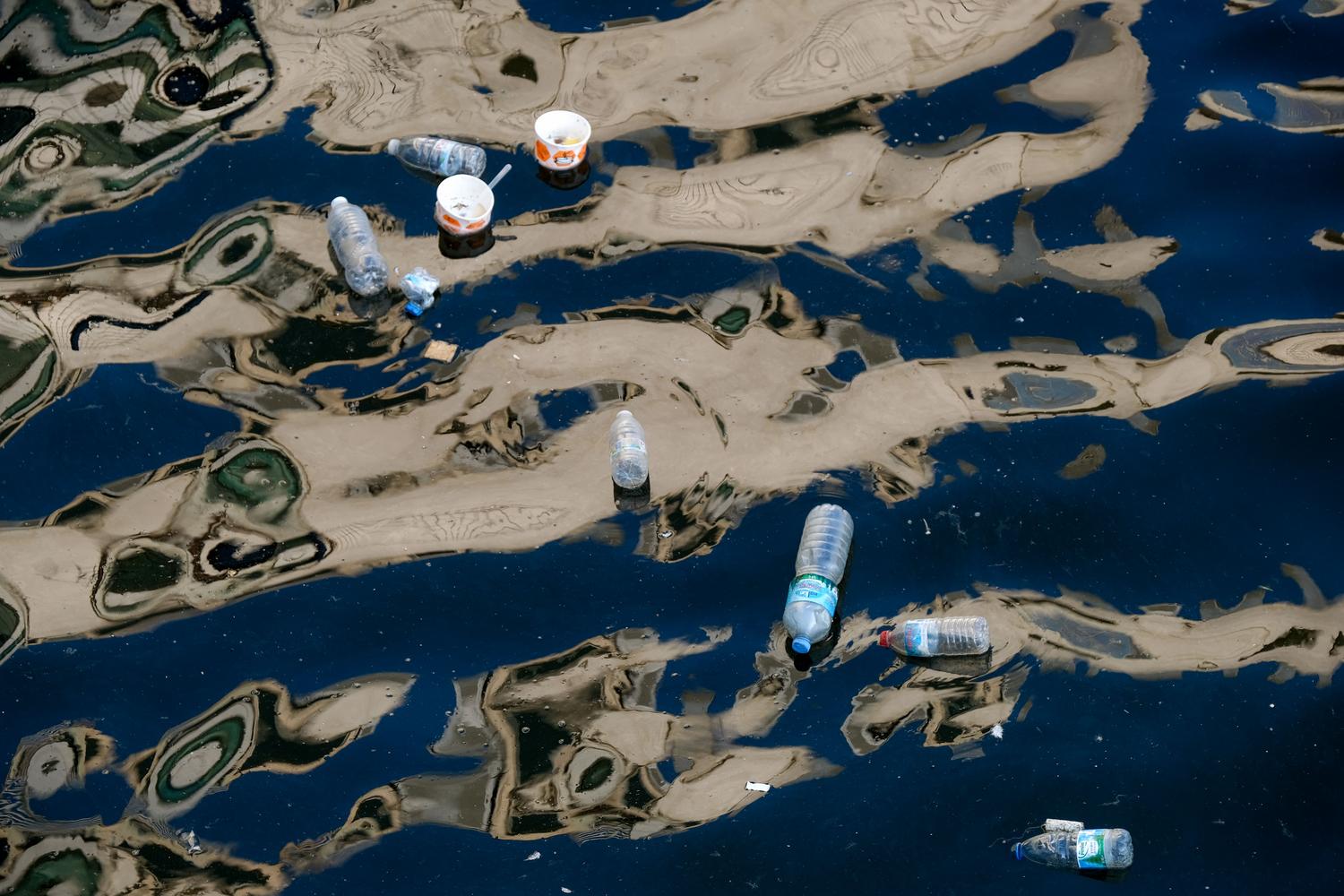 Botellas de plástico y residuos flotando en el agua, representando la materia prima recuperada del océano.