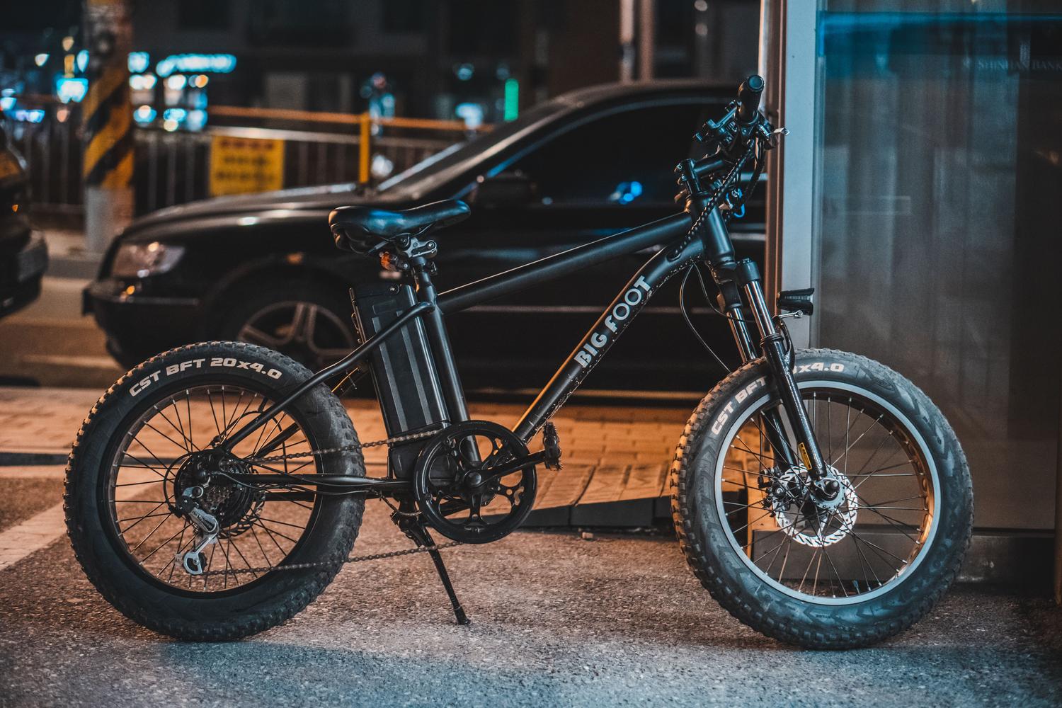 Bicicleta eléctrica moderna estacionada en una calle urbana nocturna, ilustrando la movilidad sostenible en la ciudad.