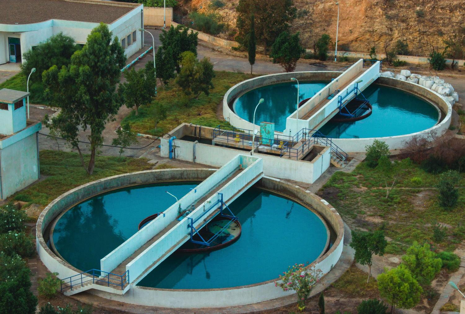 Instalación avanzada de purificación de agua rodeada de vegetación, representando el control final de contaminantes.