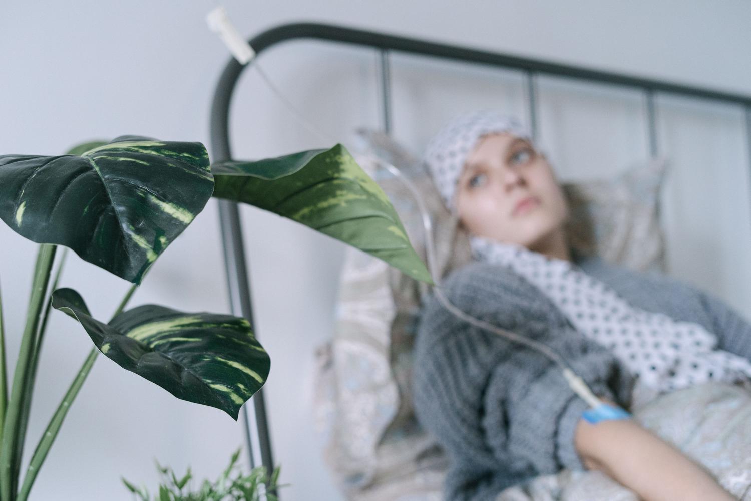 Paciente oncológica con goteo intravenoso en una cama de hospital, representando el tratamiento sistémico.