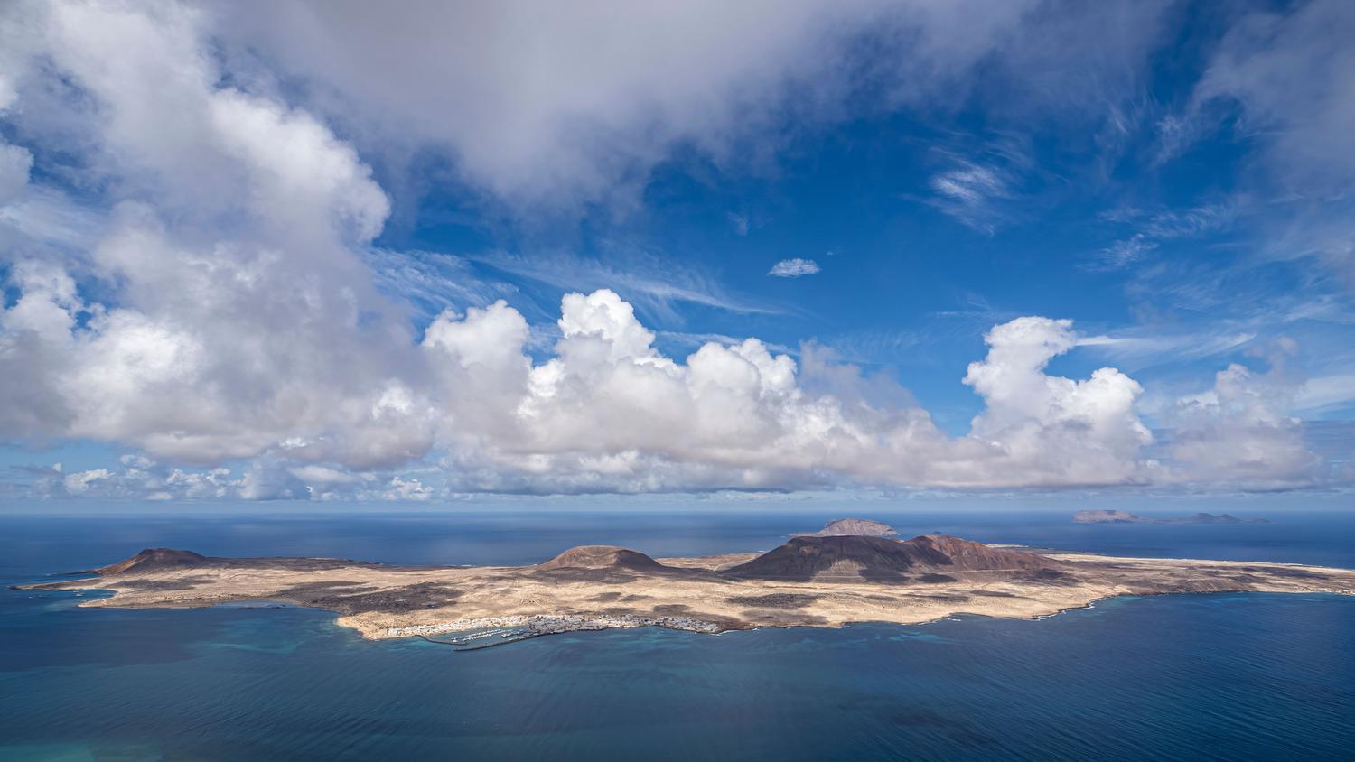 Vista aérea de la isla de La Graciosa en las Islas Canarias, resaltando su relieve árido y su interacción con el Océano Atlántico.