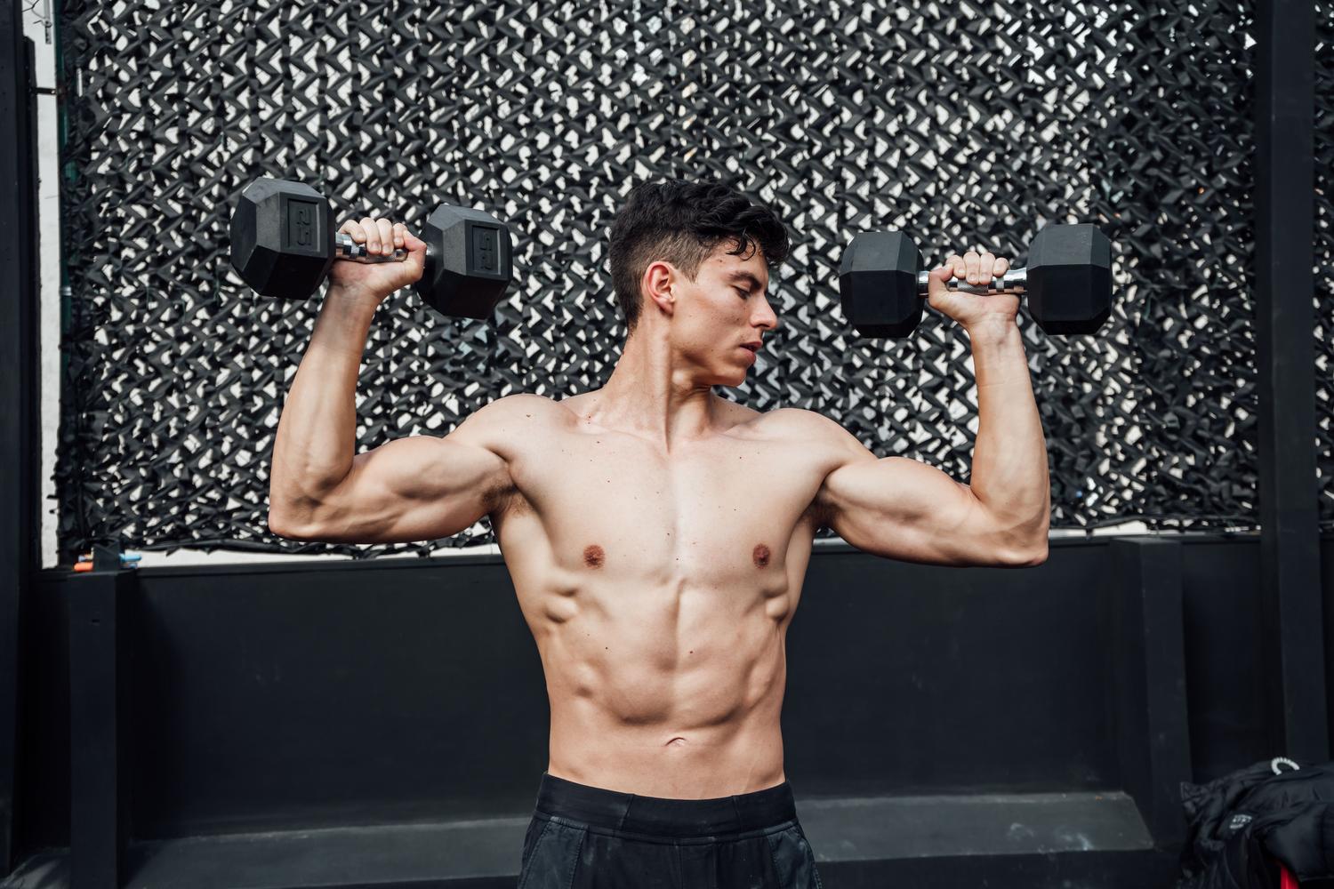 Hombre entrenando con mancuernas en el gimnasio, representando el impacto de las proteínas en la formación de masa muscular.
