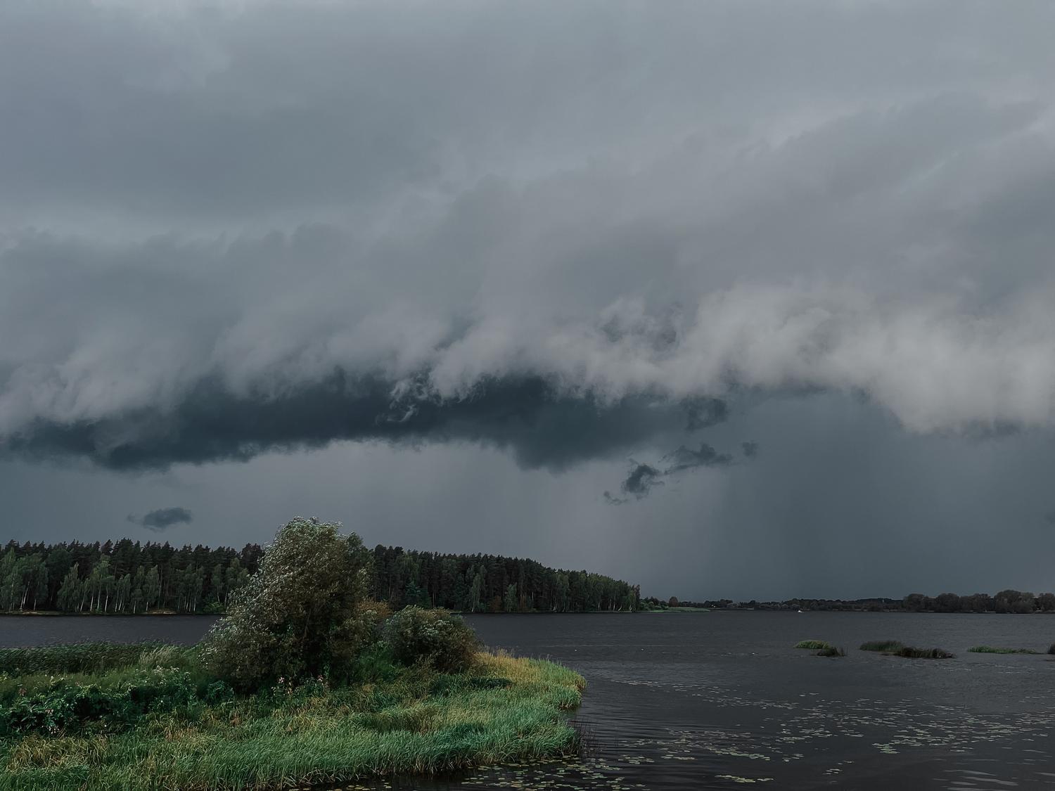Cielo dramático con densas nubes grises de tormenta sobre un lago tranquilo. Cielo dramático con densas nubes grises de tormenta sobre un lago tranquilo.
