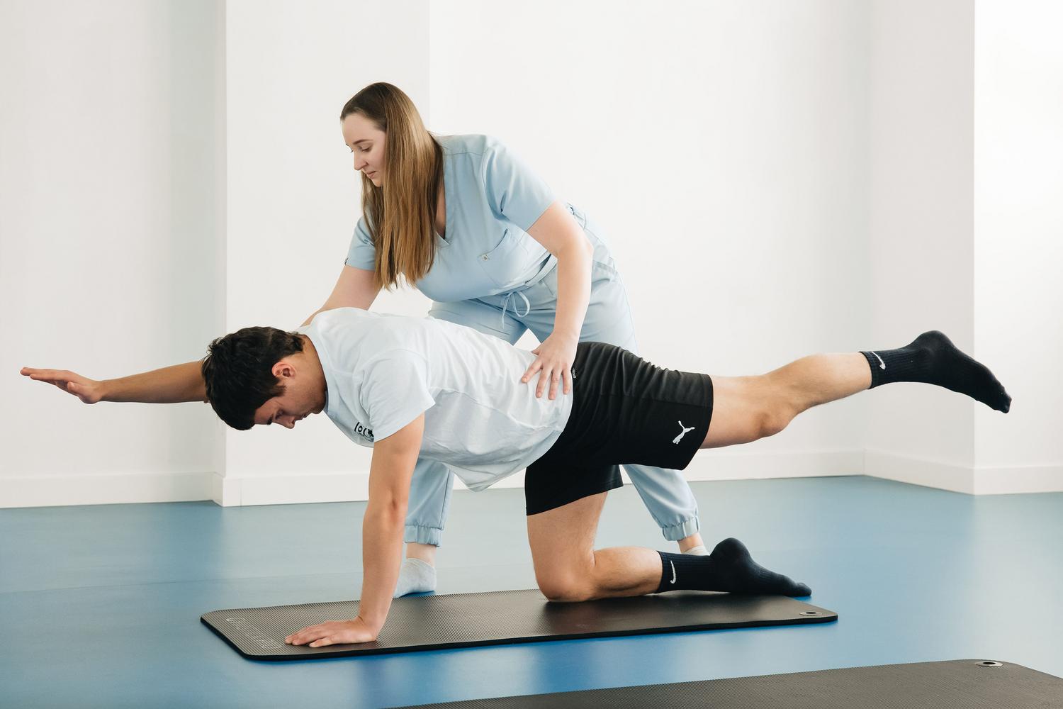 Fisioterapeuta asistiendo a un paciente en ejercicios de rehabilitación en una clínica moderna para combatir la rigidez muscular.