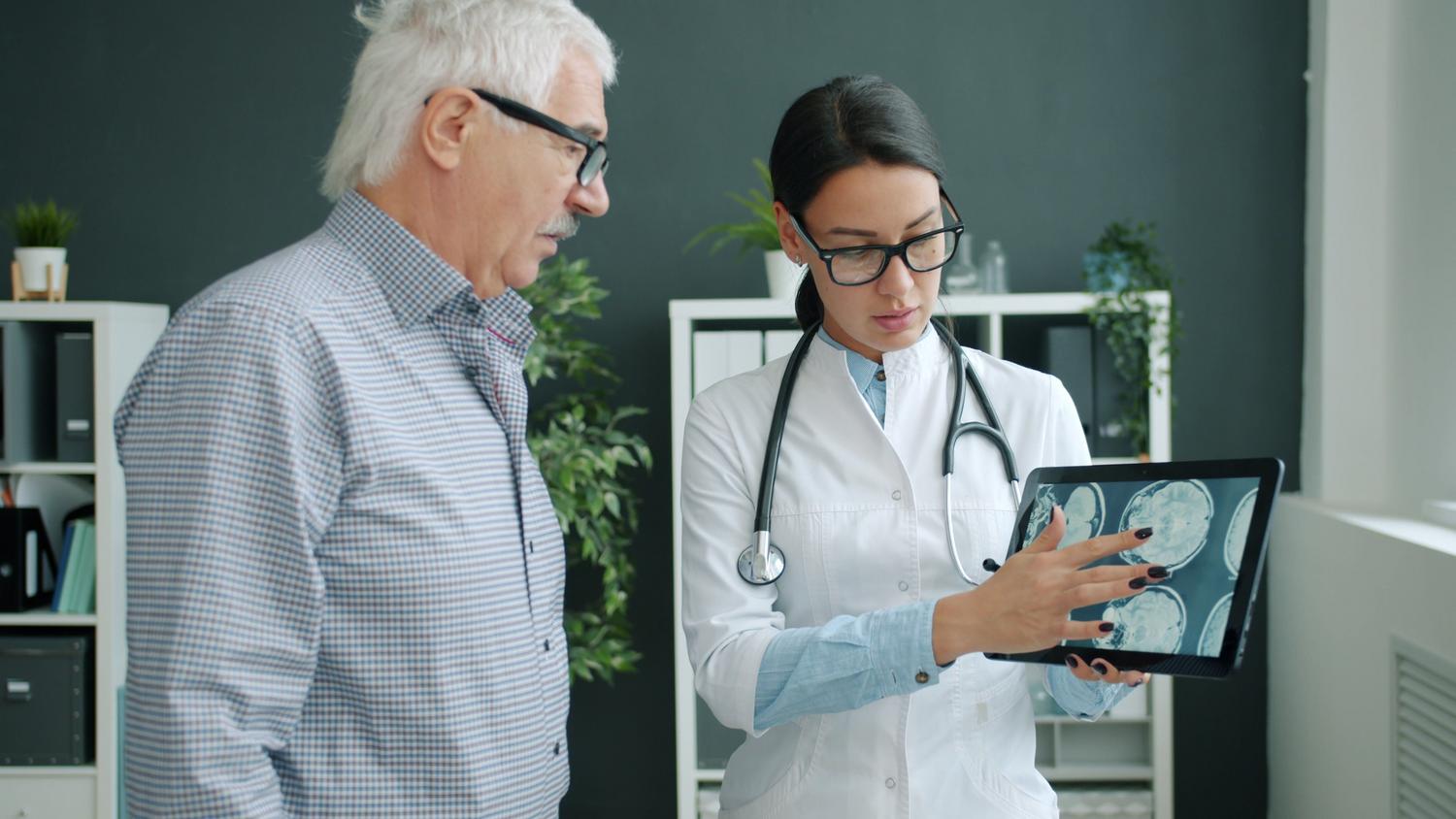 Médico neurólogo revisando escaneos cerebrales con un paciente durante una consulta para el diagnóstico de patologías neurológicas.