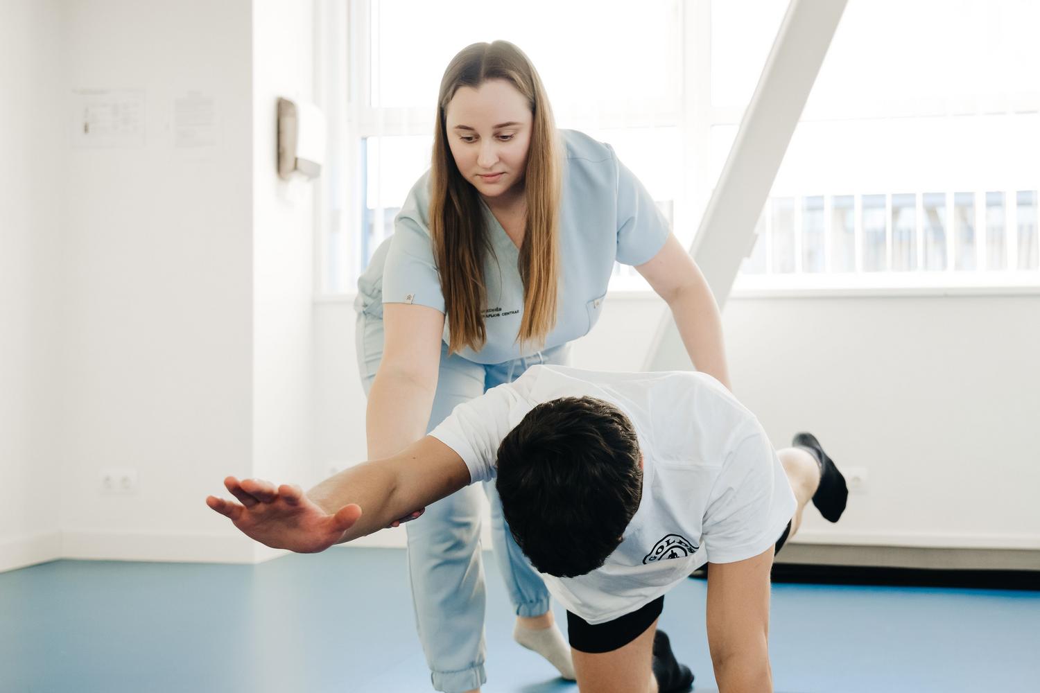 Fisioterapeuta asistiendo a un paciente en ejercicios de estiramiento para combatir la rigidez muscular.