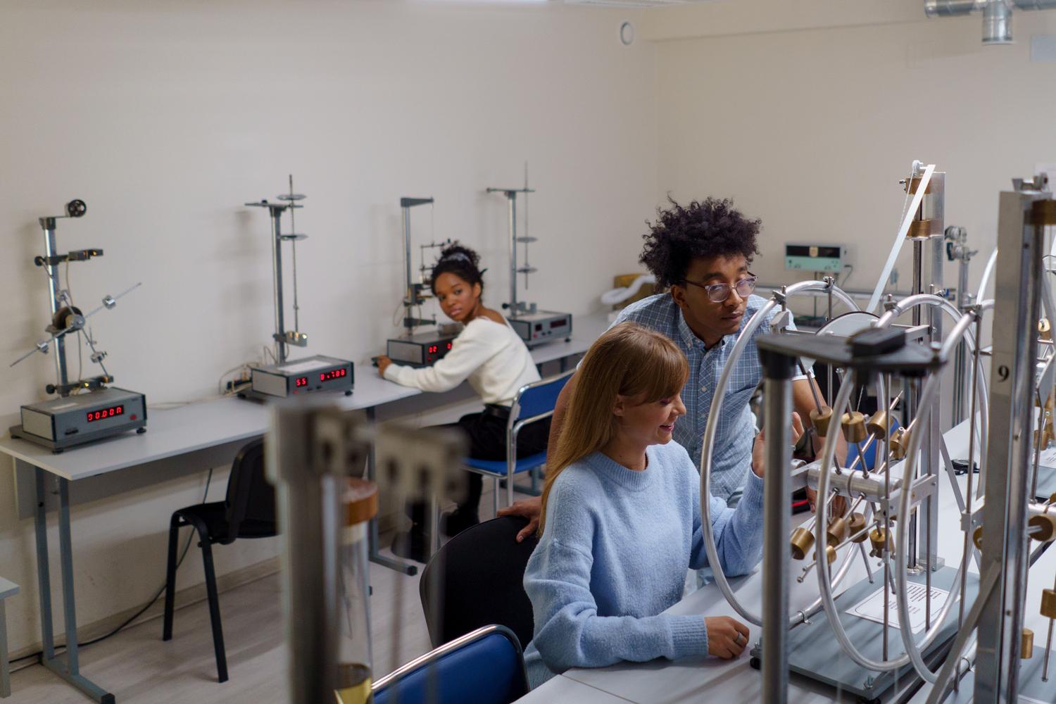 Estudiantes universitarios colaborando en experimentos de física en un laboratorio moderno, ilustrando la investigación académica en México.