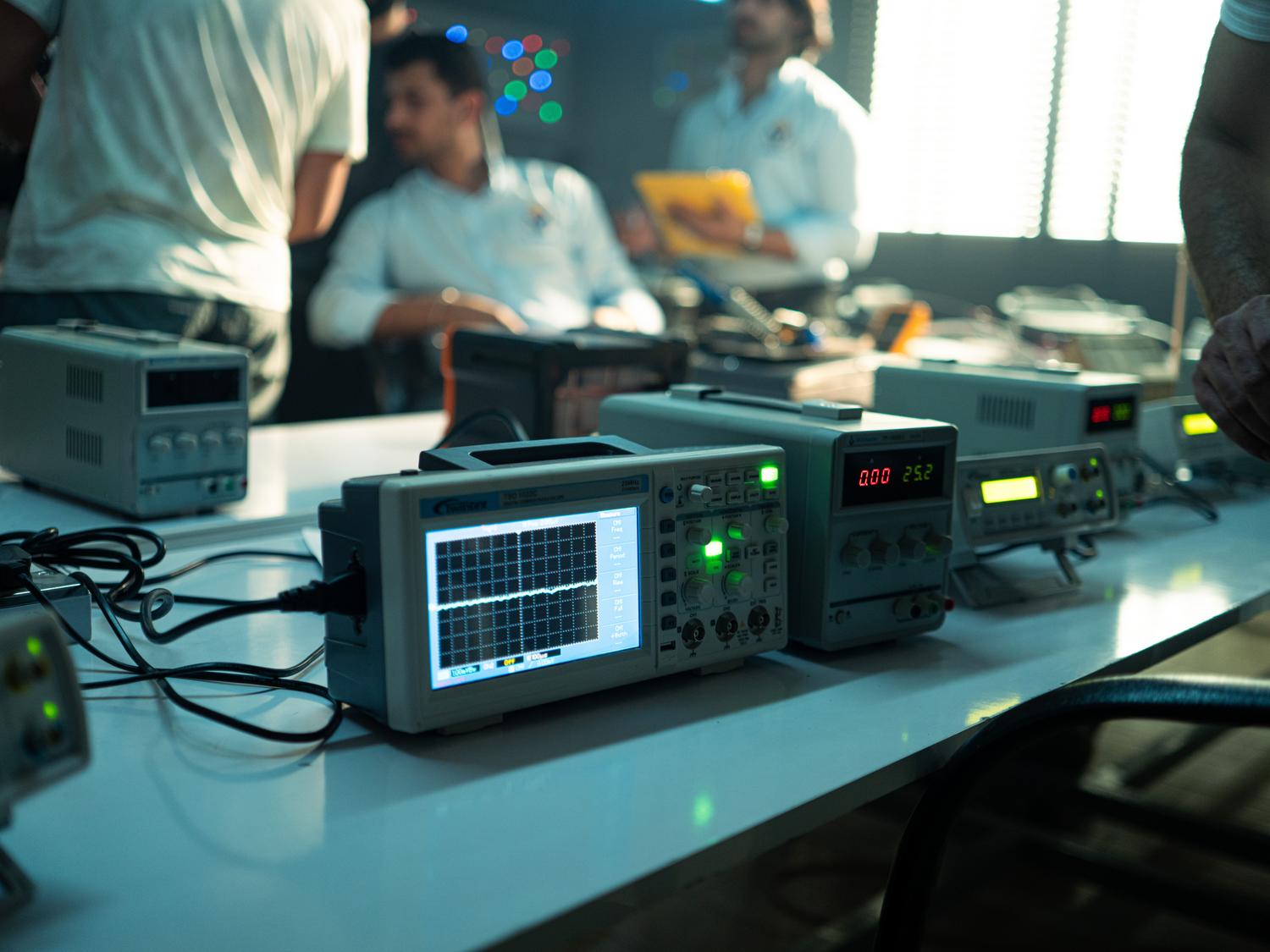 Ingenieros trabajando en un laboratorio de electrónica con osciloscopios y equipos de medición profesional.
