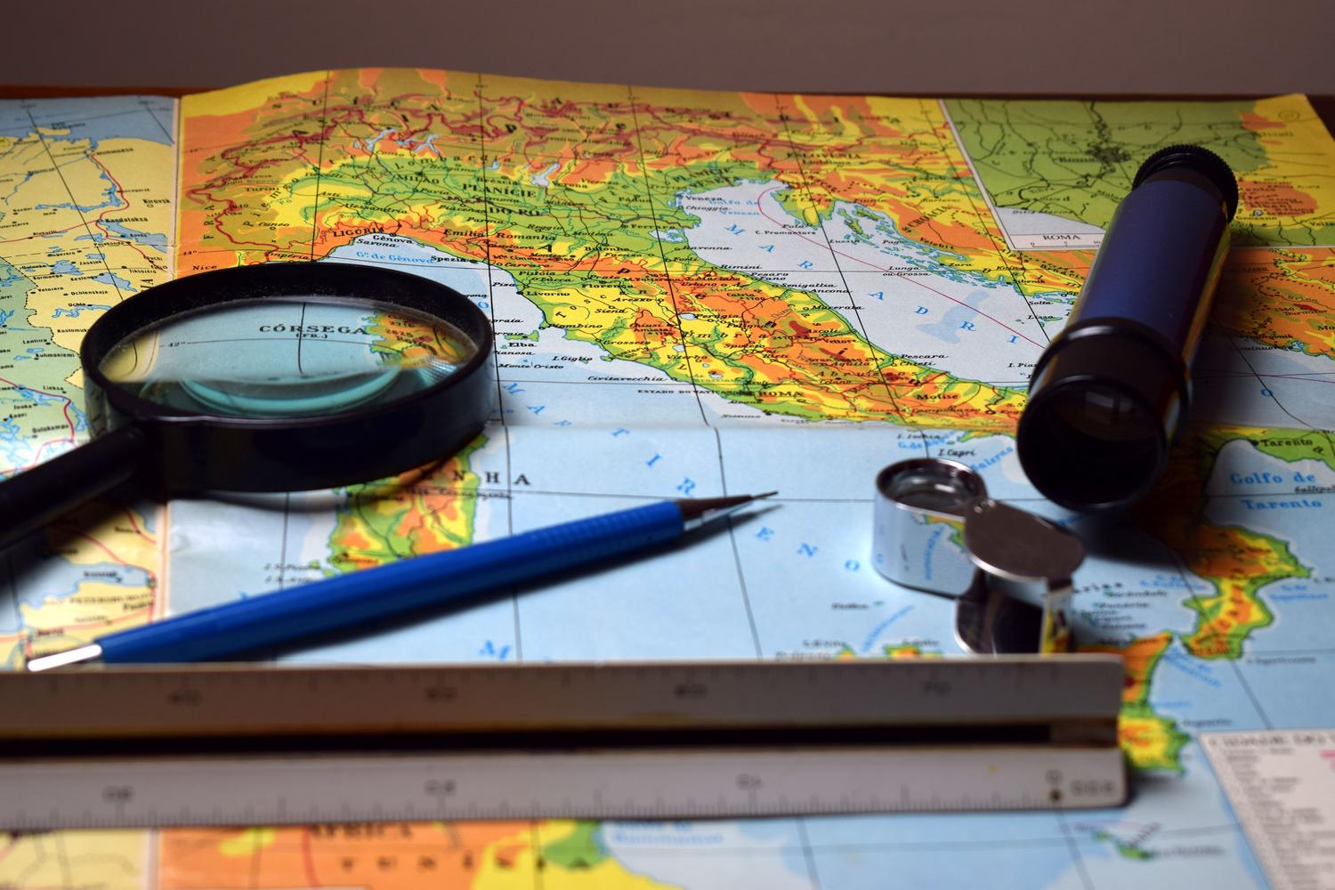 Lupa y herramientas sobre un mapa detallado, simbolizando el proceso de mapeo hidrogeológico.