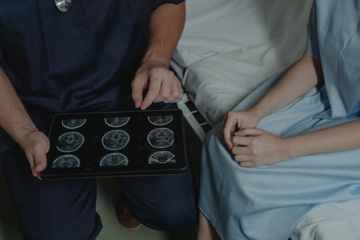 Médico explicando los resultados de un escaneo cerebral a un paciente utilizando una tableta digital.