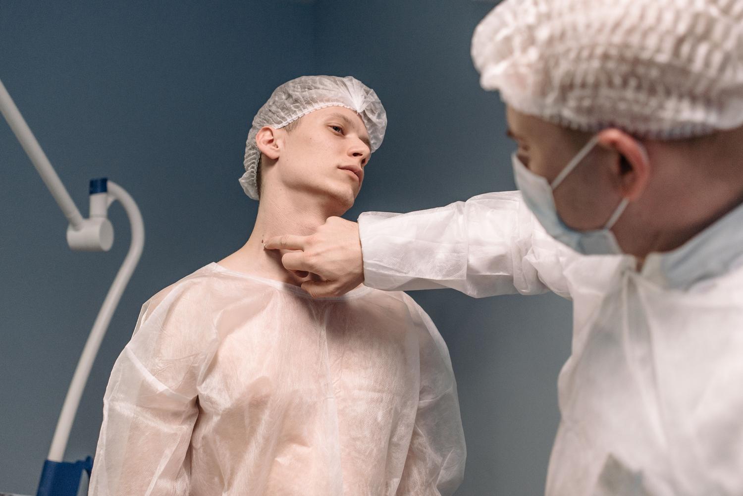 Médico especialista examinando la zona del cuello de un paciente para evaluar la glándula tiroides y la glándula parótida.