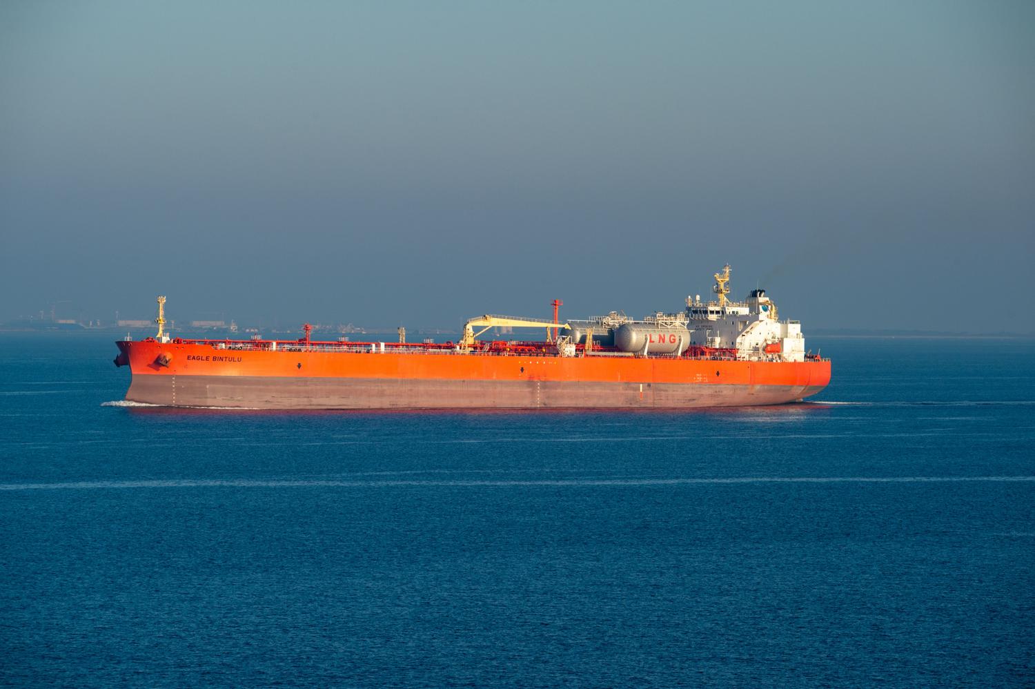 Buque transportador de GNL de color naranja navegando en un mar tranquilo en un día despejado