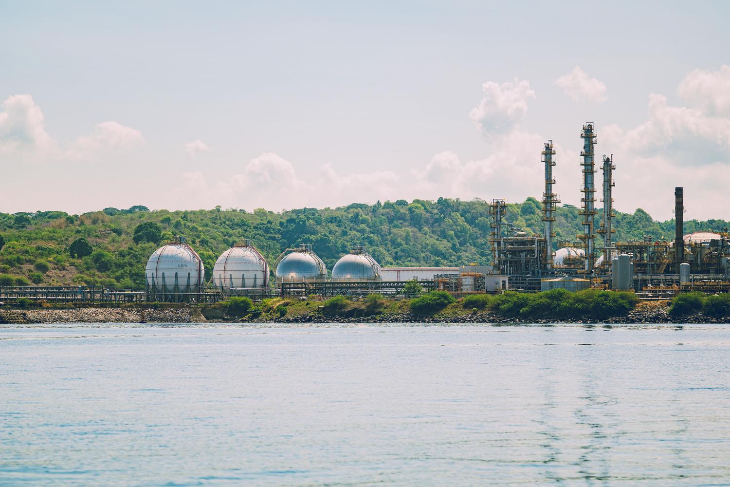 Instalación industrial de almacenamiento de gas en la costa con tanques esféricos y chimeneas altas Instalación industrial de almacenamiento de gas en la costa con tanques esféricos y chimeneas altas