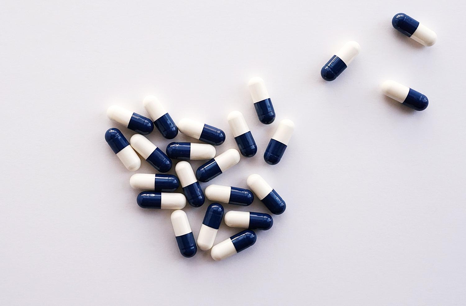 Cápsulas farmacéuticas sobre fondo blanco, representando las terapias dirigidas orales como los inhibidores de BTK.
