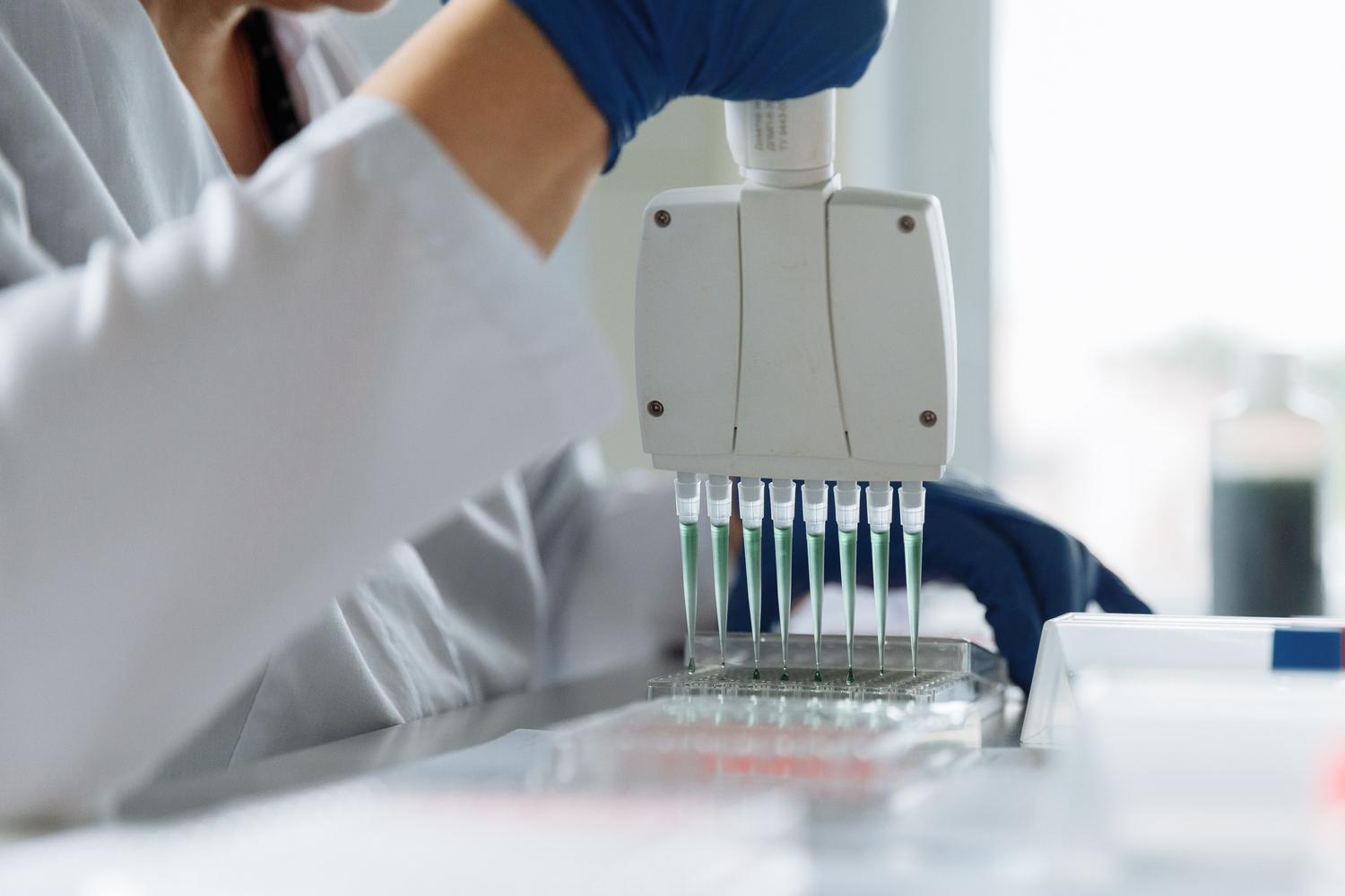 Uso de pipeta multicanal en laboratorio, representando la precisión requerida en la edición genómica y la terapia génica.